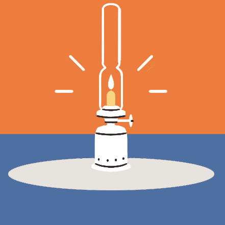 Lit oil lamp with glass chimney and flame on a white circular surface against blue background