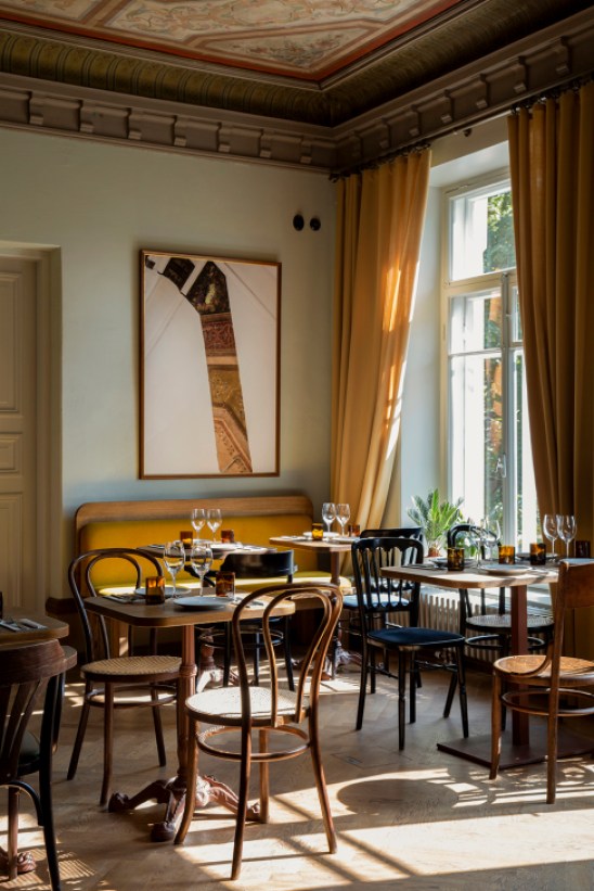 Elegant dining room interior at Restaurant Elm in Helsinki showing restored 19th-century villa architecture with decorative ceiling painting