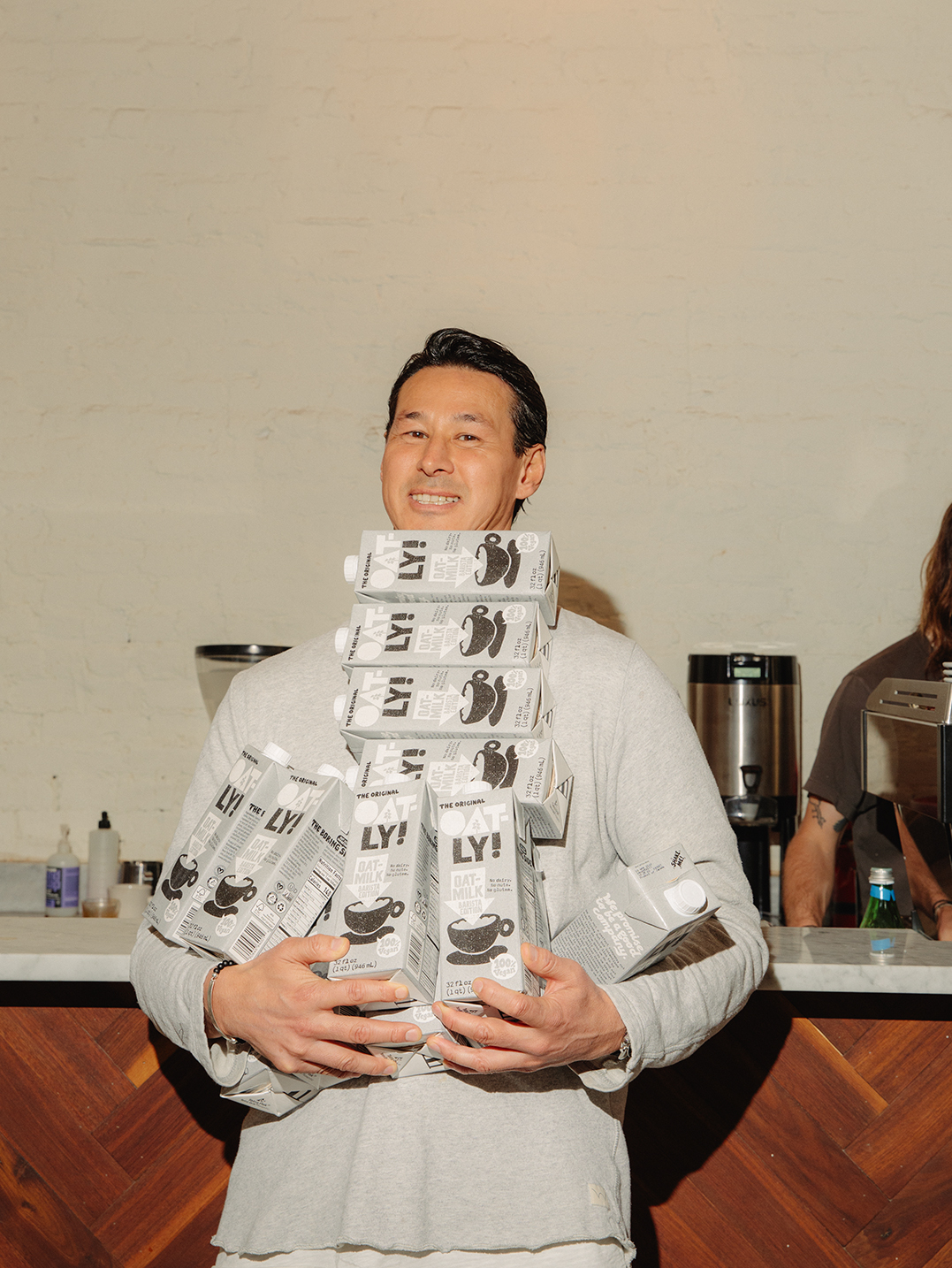 Toni Petersson holding stacks of Oatly oat milk cartons with distinctive packaging