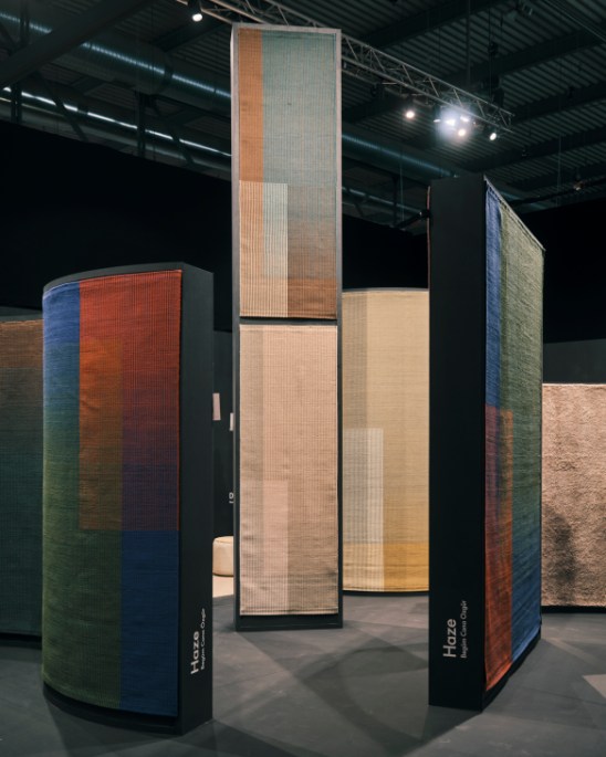 Tall vertical rug displays showing Haze collection by Nanimarquina with gradient wool colors at furniture fair