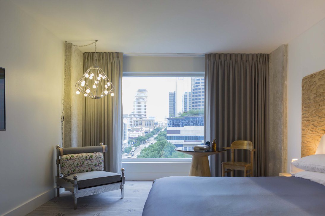 Hotel room at The Line Austin with modern furnishings and large windows overlooking downtown Austin cityscape