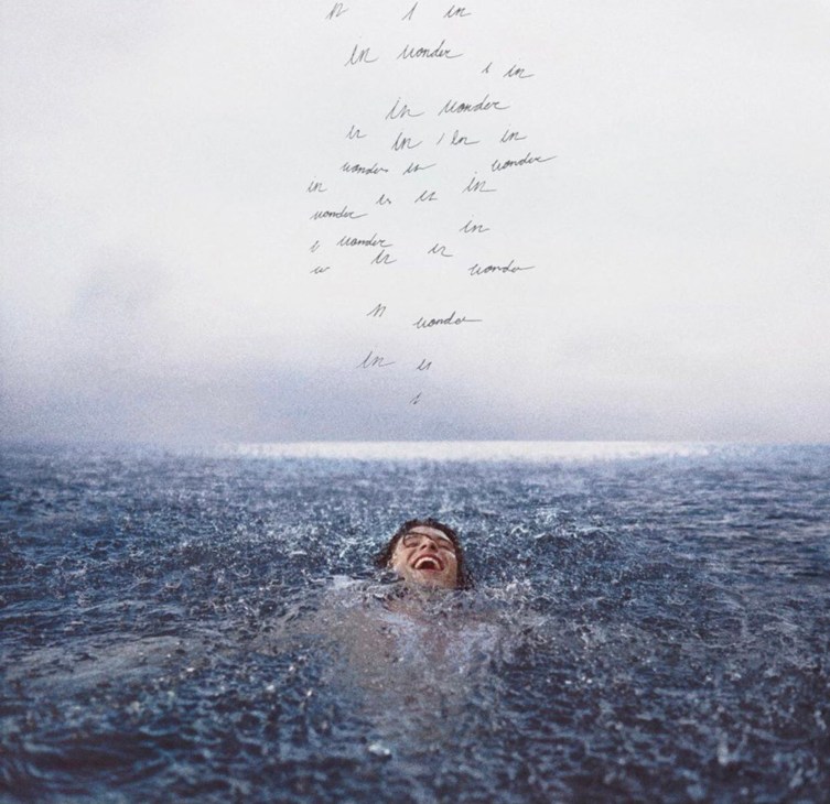 Person swimming joyfully in ocean water with handwritten text scattered above