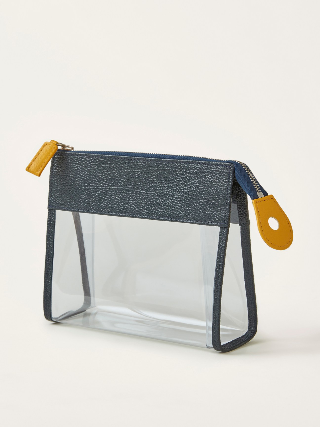 See-through travel toiletry pouch by R Horn's x Monocle with charcoal textured top, clear body, and yellow leather accents.