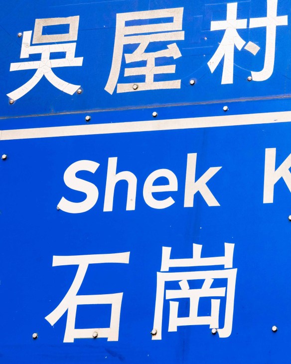 Blue and white bilingual street sign with Chinese characters and English text 'Shek Kiu' below