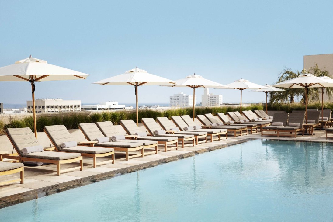 Rooftop pool at Santa Monica Proper Hotel with lounge chairs, umbrellas and city views