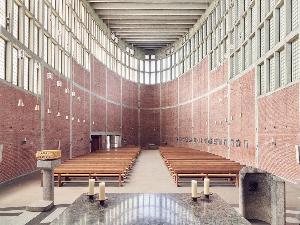 Interior of St Theresia church in Linz showing brick walls, wooden pews, and glass panels allowing natural light