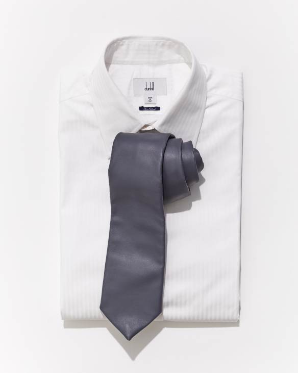 Gray necktie arranged on white dress shirt against neutral background