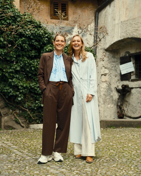 Anna and Helena Lageder standing together smiling in a courtyard at their family winery