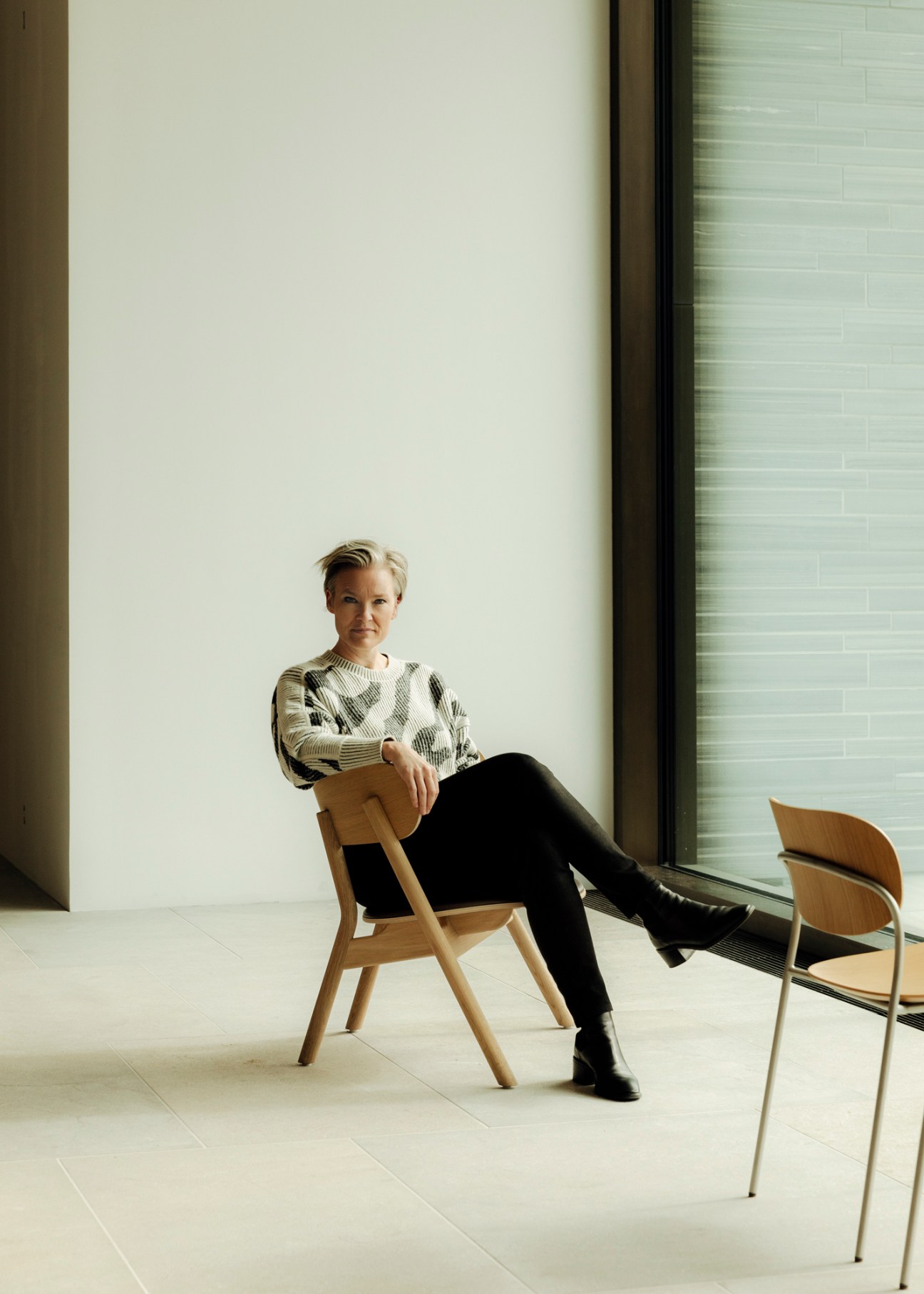 Yngvill Sjösteen sitting in modern wooden chair in minimalist white museum space