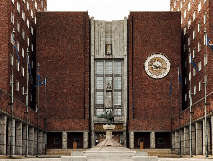 Oslo City Hall entrance showing red-brown brick facade with twin towers, central clock, and symmetrical design