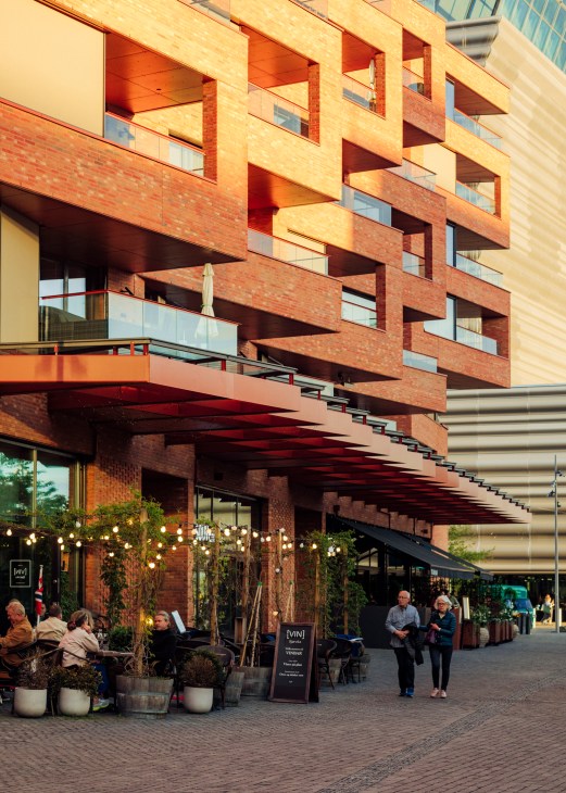 Modern brick residential building with distinctive staggered balconies and geometric facade design