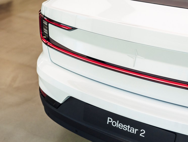 Close-up of white Polestar 2 electric vehicle's rear end showing red LED taillight and black bumper with model name