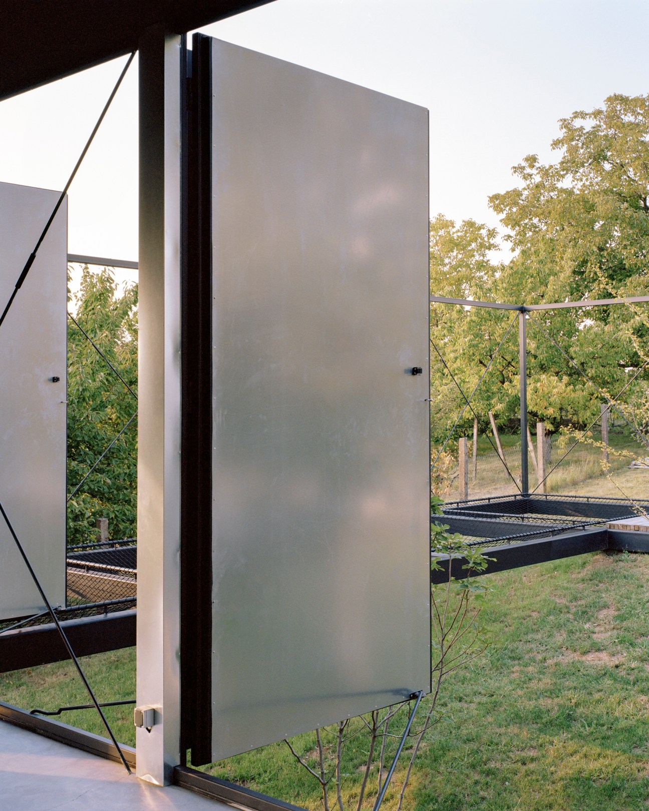 Modern sustainable house at dusk with large glass windows integrated into natural mountain landscape