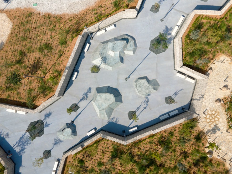 Aerial view of modern skate park with concrete bowls and ramps surrounded by desert landscaping