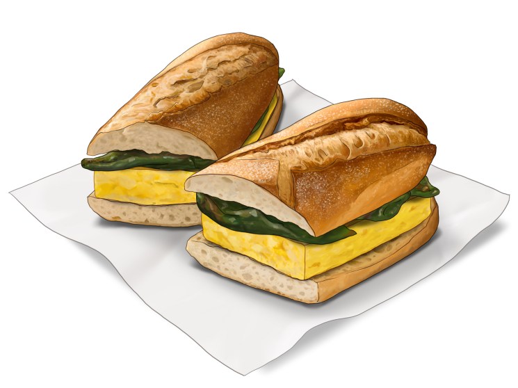 Two tortilla bocadillo sandwiches cut in half showing yellow egg filling and green peppers on white paper