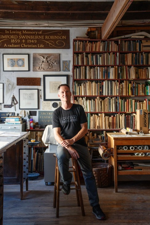 Nicholas Benson, owner of The John Stevens Shop, standing in his stone carving workshop surrounded by tools