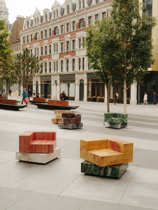 Colorful geometric stone seating installations in urban plaza with historic architecture