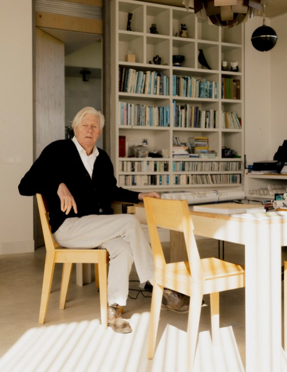 Piet Oudolf sitting at a wooden table in his home office with built-in bookshelves