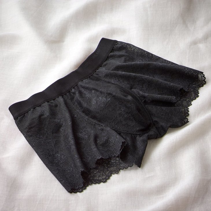 Black lace boxer underwear for men displayed on white fabric background
