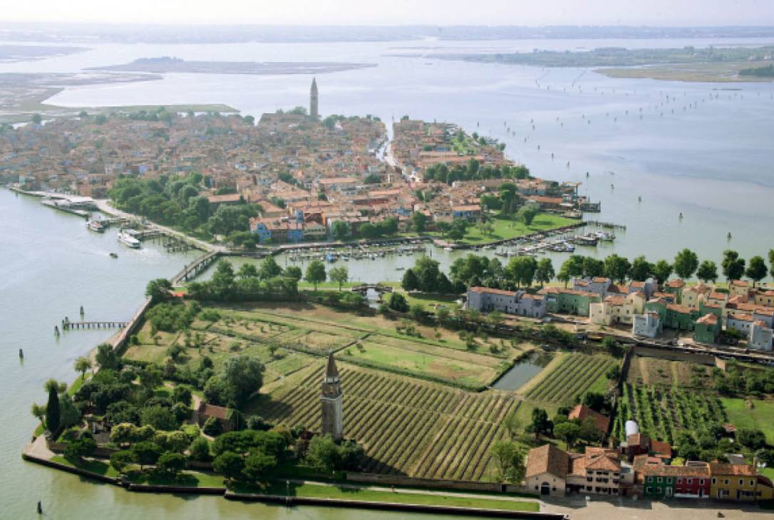 Aerial view of Venissa estate vineyard on Mazzorbo island with bell tower, surrounding lagoon and colorful buildings
