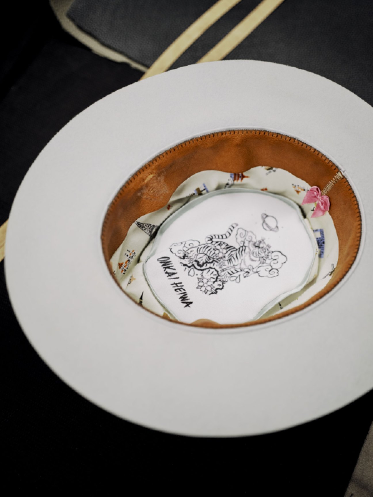 Interior view of white cowboy hat showing brown leather band and decorative lining with tiger illustration