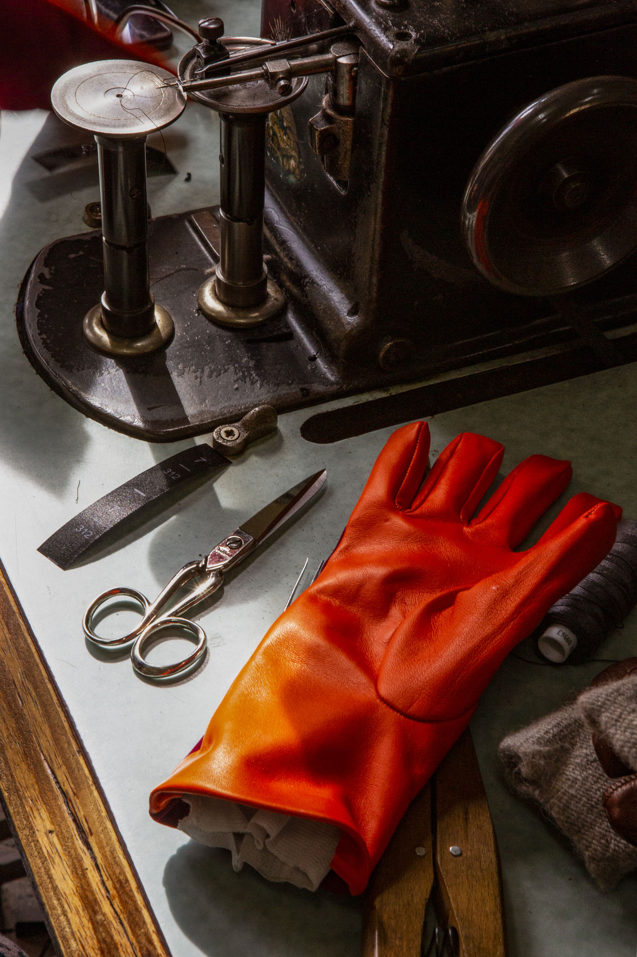 Red leather glove on a workbench beside scissors and craft tools.