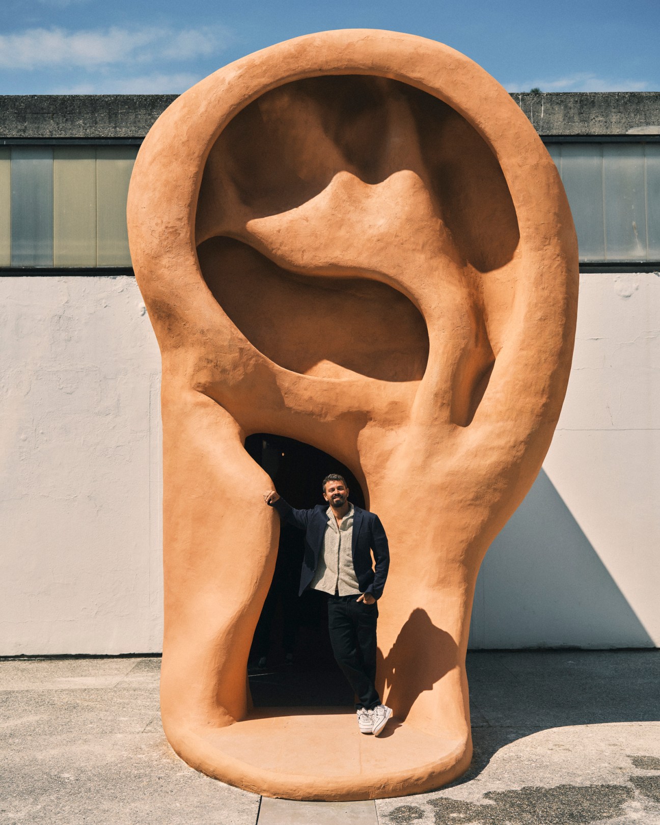 Brazilian artist Jonathas de Andrade standing inside a large sculptural ear installation at Venice Biennale