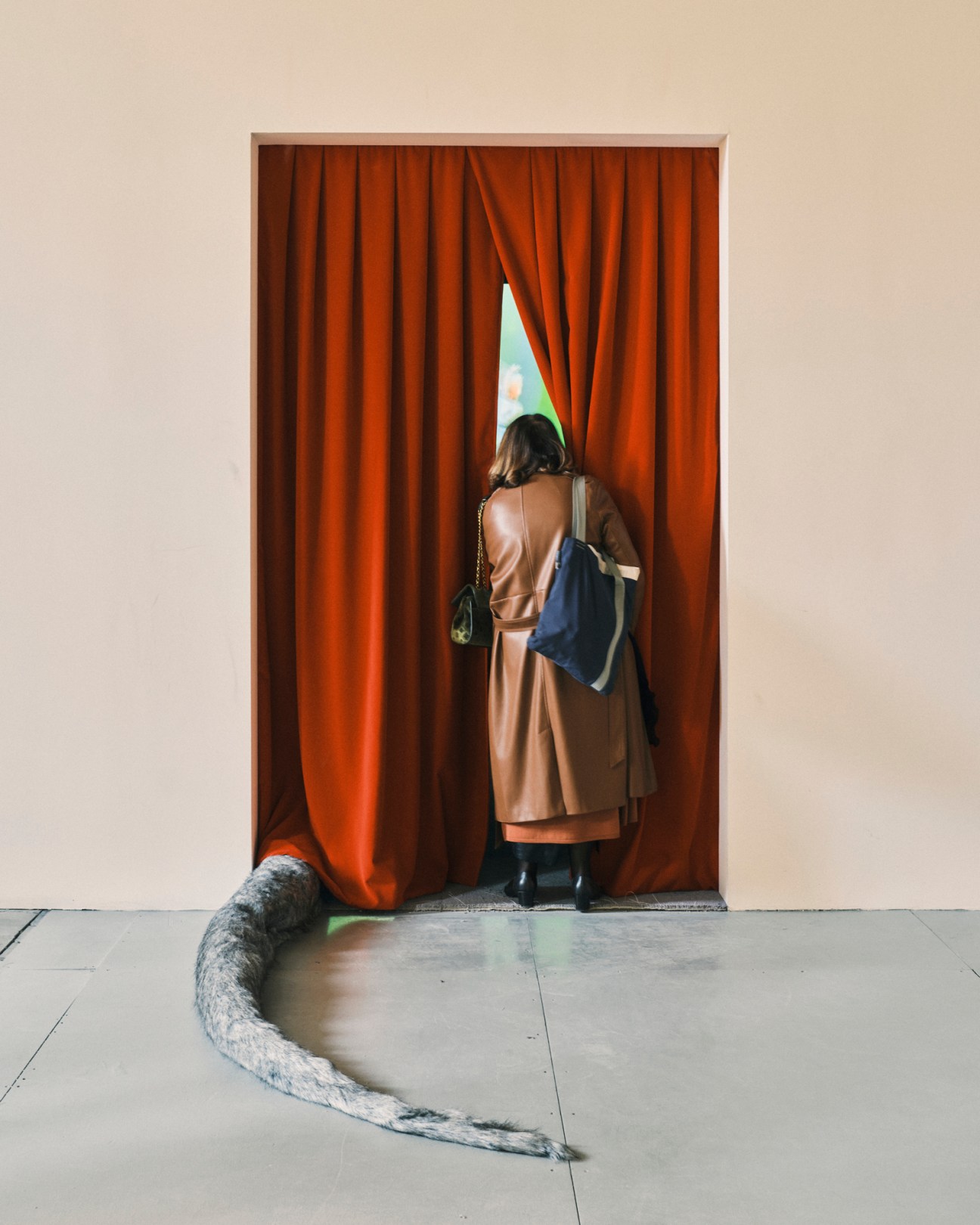 Person peeking through gap in red curtains in gallery doorway