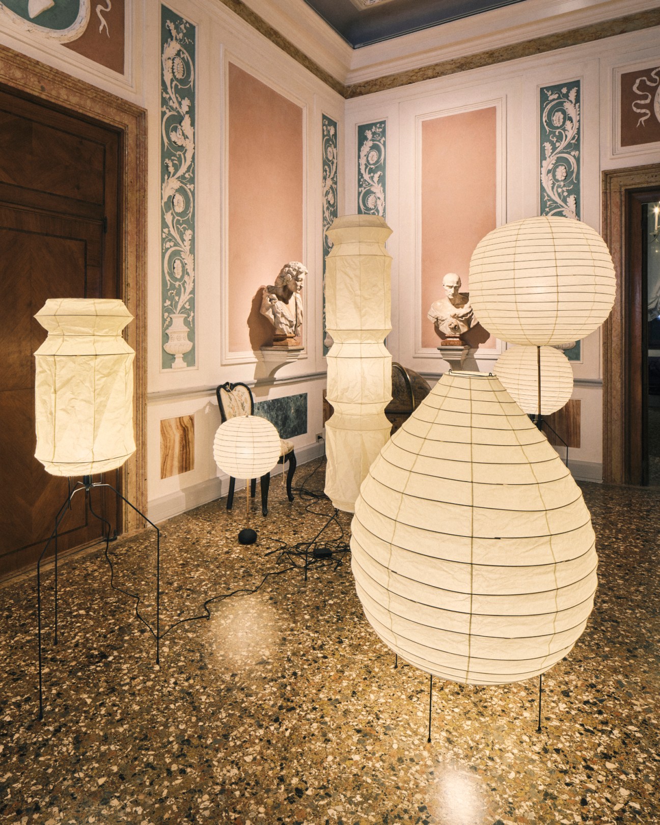 Light sculptures by Isamu Noguchi displayed in a classical architectural interior with ornate columns and decorative walls