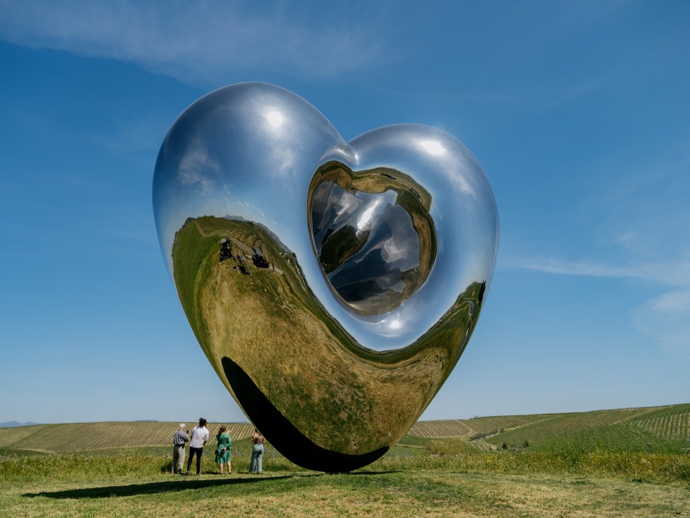 Richard Hudson's reflective heart-shaped sculpture 'Love Me' positioned on a hillside at Donum Estate vineyard