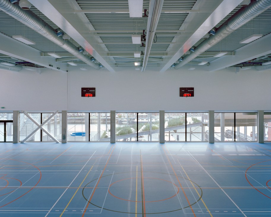 Interior of Melopee school in Ghent showing a minimalist metal skeleton structure with transparent steel grid and open public space.