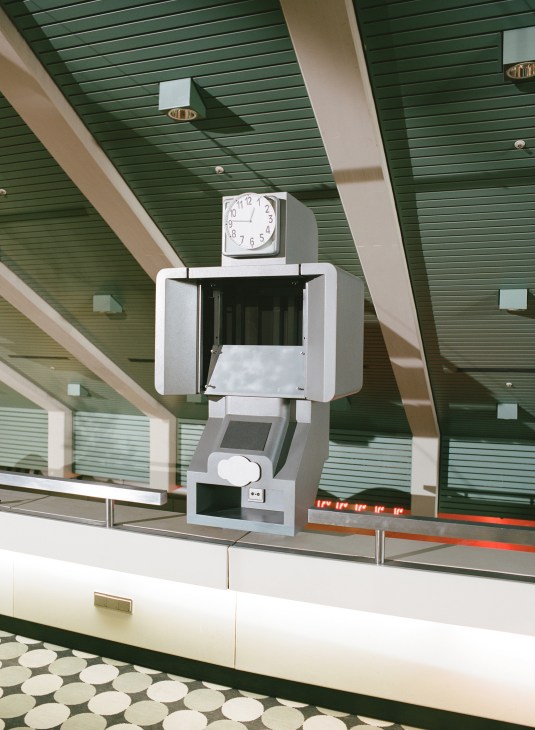 Retro information kiosk with clock and green slat ceiling at the International Congress Centre