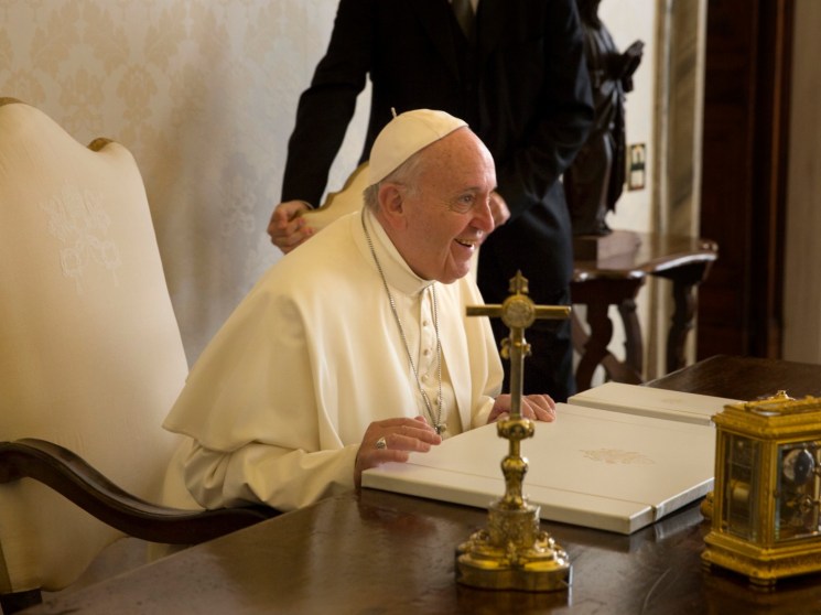 Pope Francis sitting at a table.
