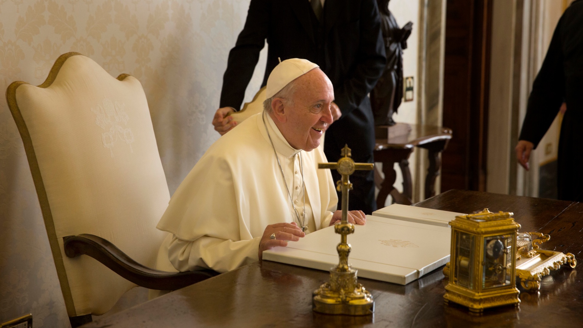 Pope Francis sitting at a table.