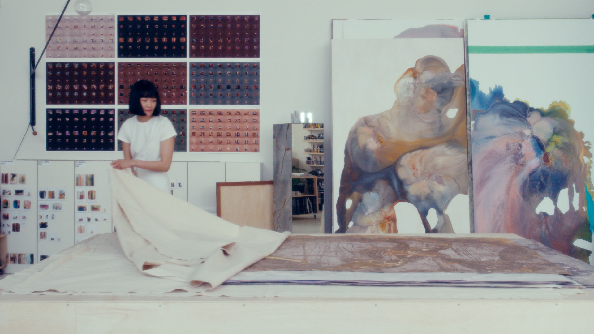 An artist revealing a painting in her studio