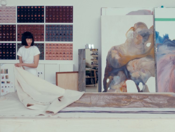 An artist revealing a painting in her studio