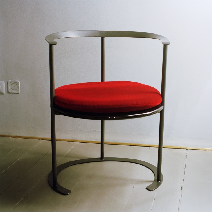 Catilina chair with red cushion seat and curved metal frame in Azucena showroom
