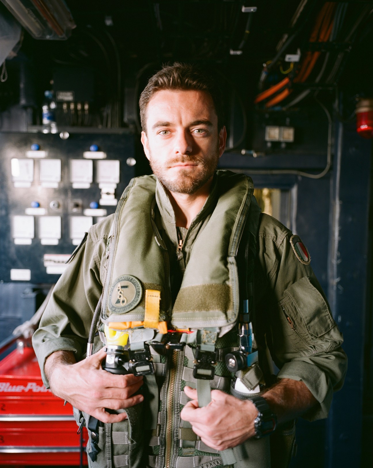 Helicopter pilot Riccardo Ferri in flight suit standing in aircraft interior.