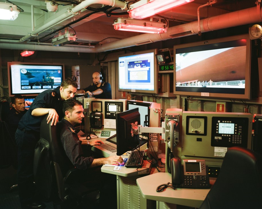 Military personnel monitor screens and workstations in the operations room of the Italian aircraft carrier Cavour.