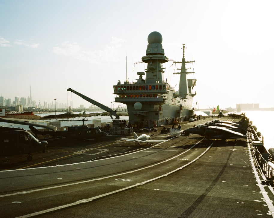 Italian aircraft carrier Cavour moored in Dubai port with city skyline in background.