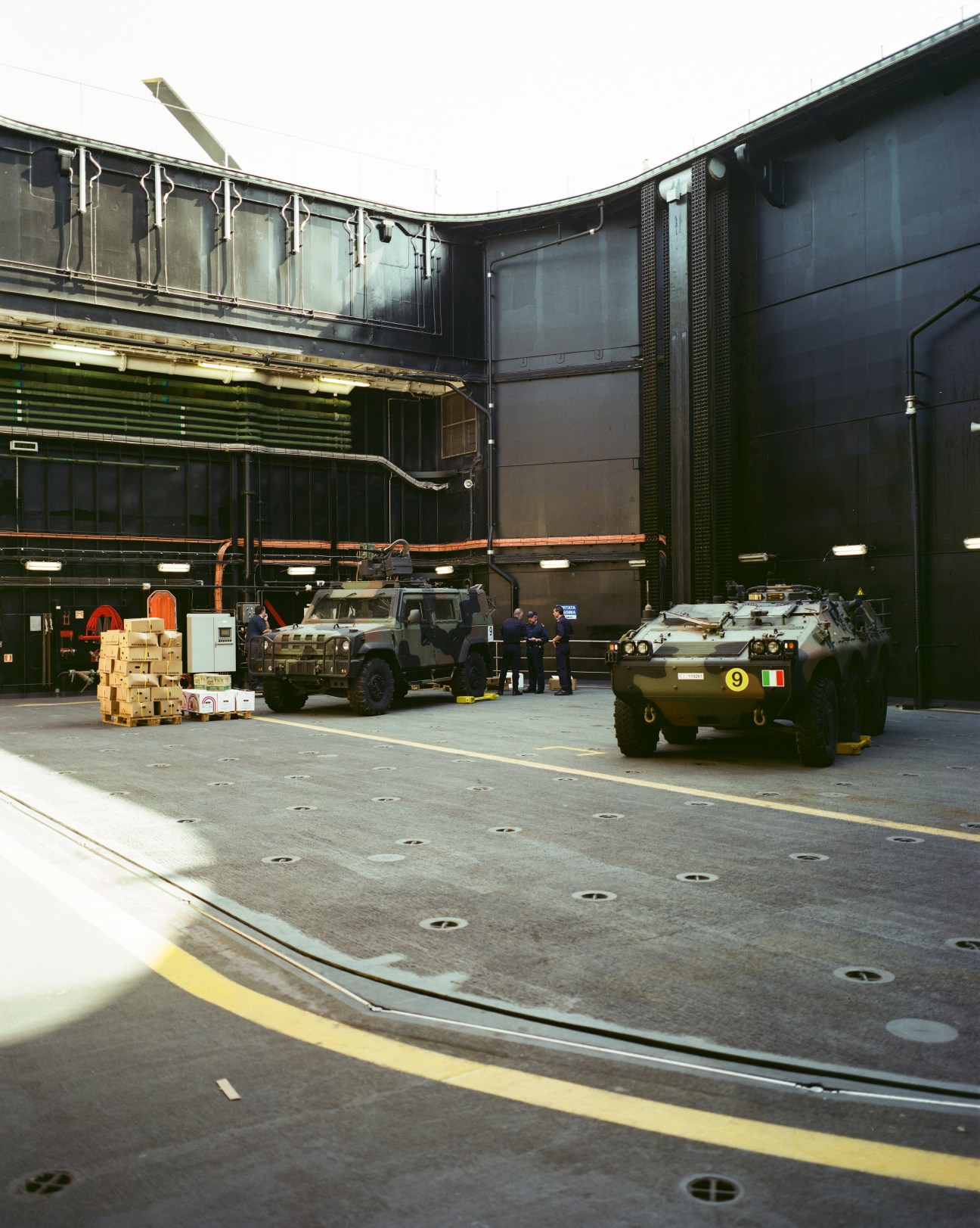 Italian military combat vehicles and personnel inside the Cavour aircraft carrier's hangar on a 30-tonne elevator.
