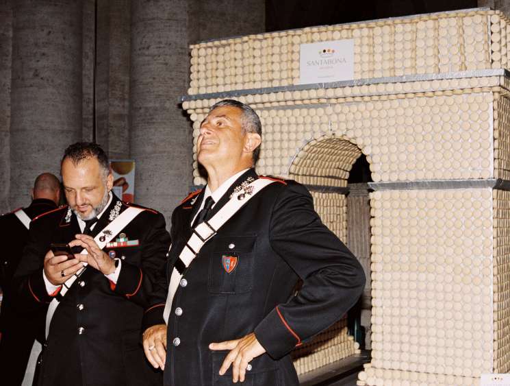 Two Italian carabinieri officers in formal dress uniforms looking upward at French embassy celebration