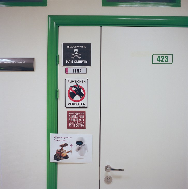 A green-framed door numbered 423 with various stickers including warning signs and humorous decals.