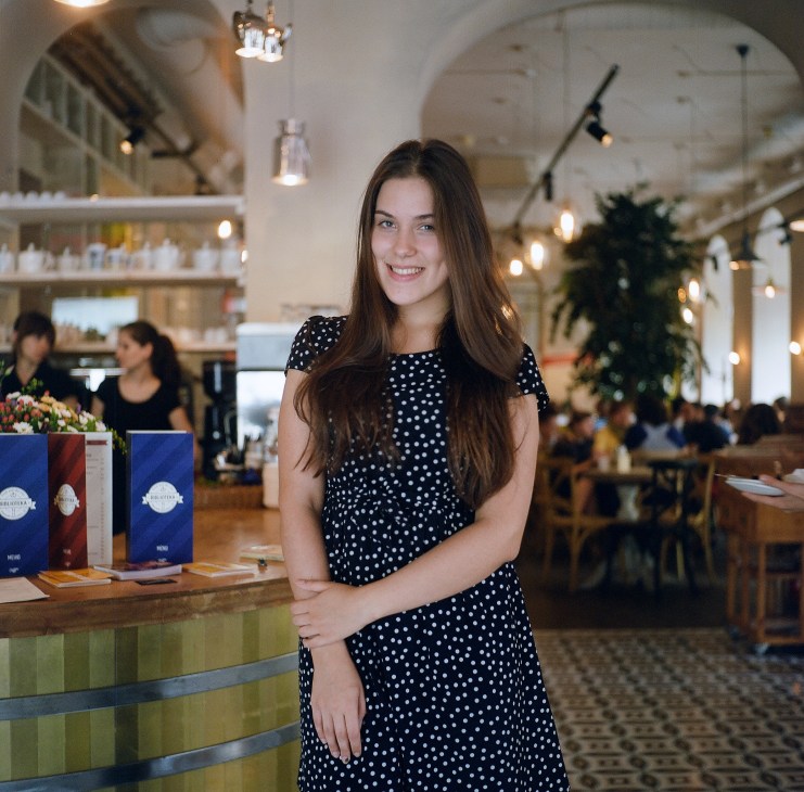 A waitress in a polka dot dress stands at the counter of Biblioteka Restaurant in St Petersburg.