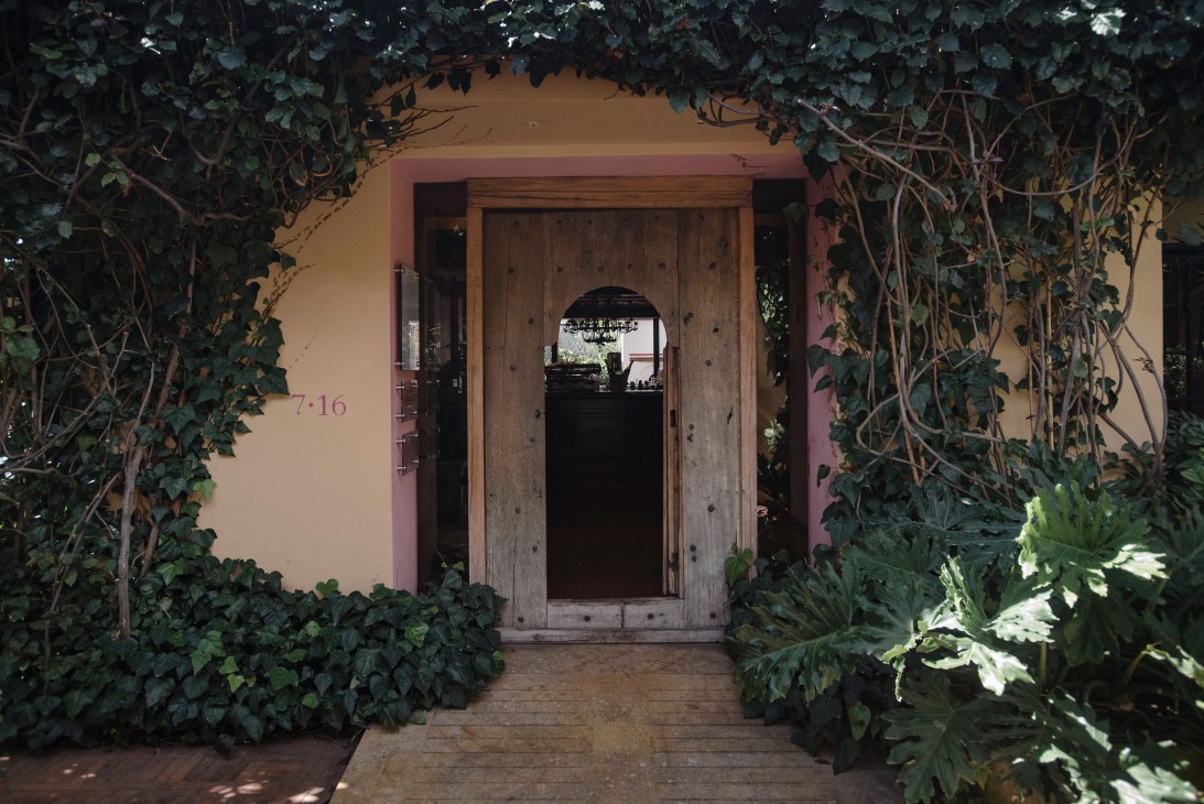 Ivy-covered entrance to 7.16 restaurant with wooden door and pale pink walls in Usaquén, Bogotá.