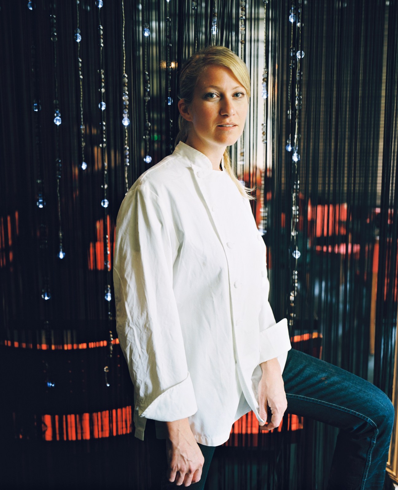 Karen Bell, a chef from Wisconsin, poses in front of hanging beaded curtains in her Madrid restaurant.