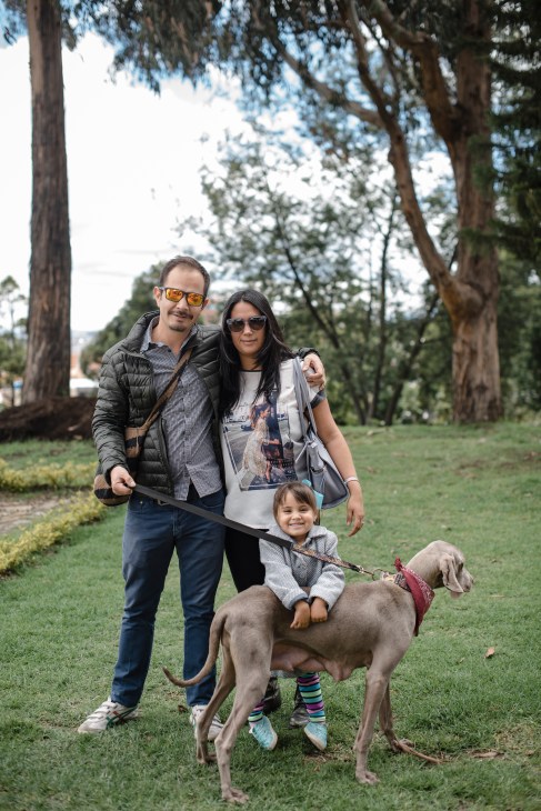Family with child and dog standing under tall eucalyptus trees in a park in Bogotá's Usaquén neighborhood.