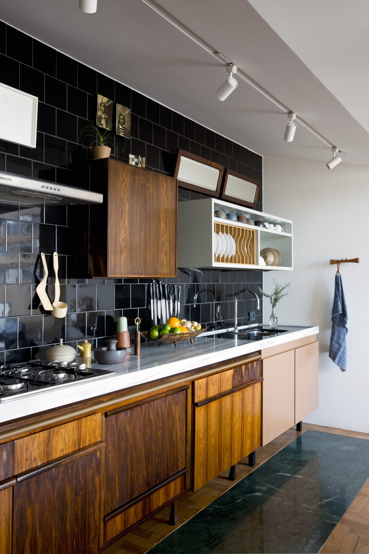 Modern kitchen with black subway tile backsplash, wooden cabinetry, white countertop, and stainless steel appliances in Marcelo Alvarenga's apartment.