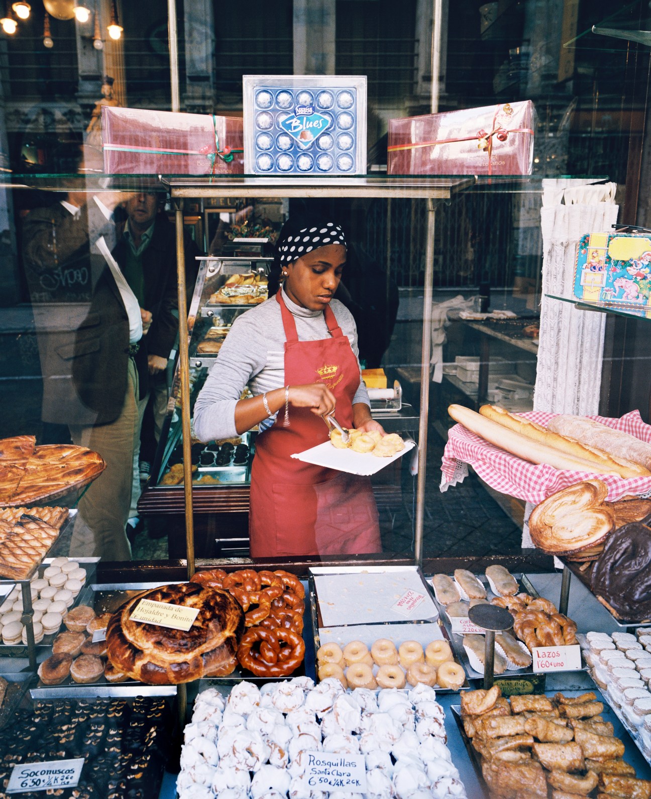 Baker arranging pastries in La Mallorquina bakery window on Calle Mayor, Madrid.