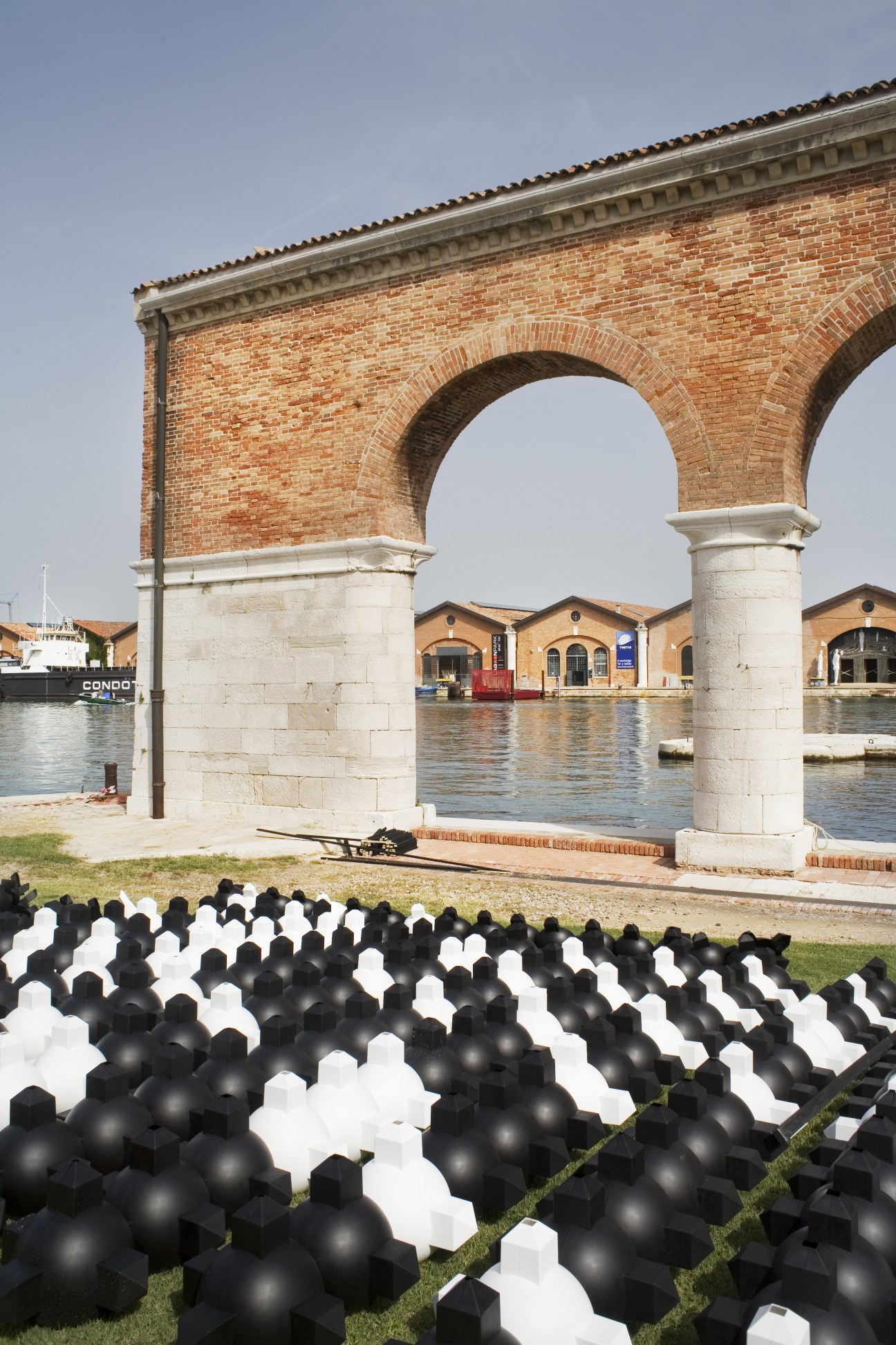 The Arsenale in Venice with brick archway and black-and-white sphere installation.
